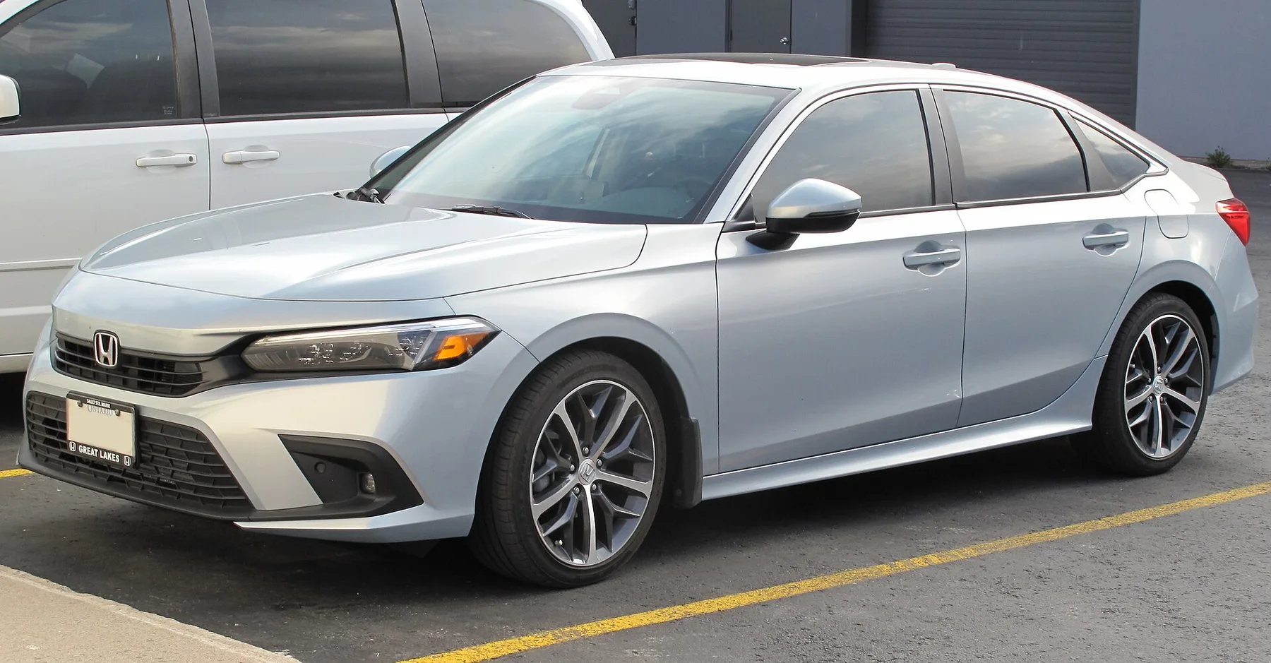 Silver eleventh-generation Honda Civic sedan parked in a car park, seen from the front left