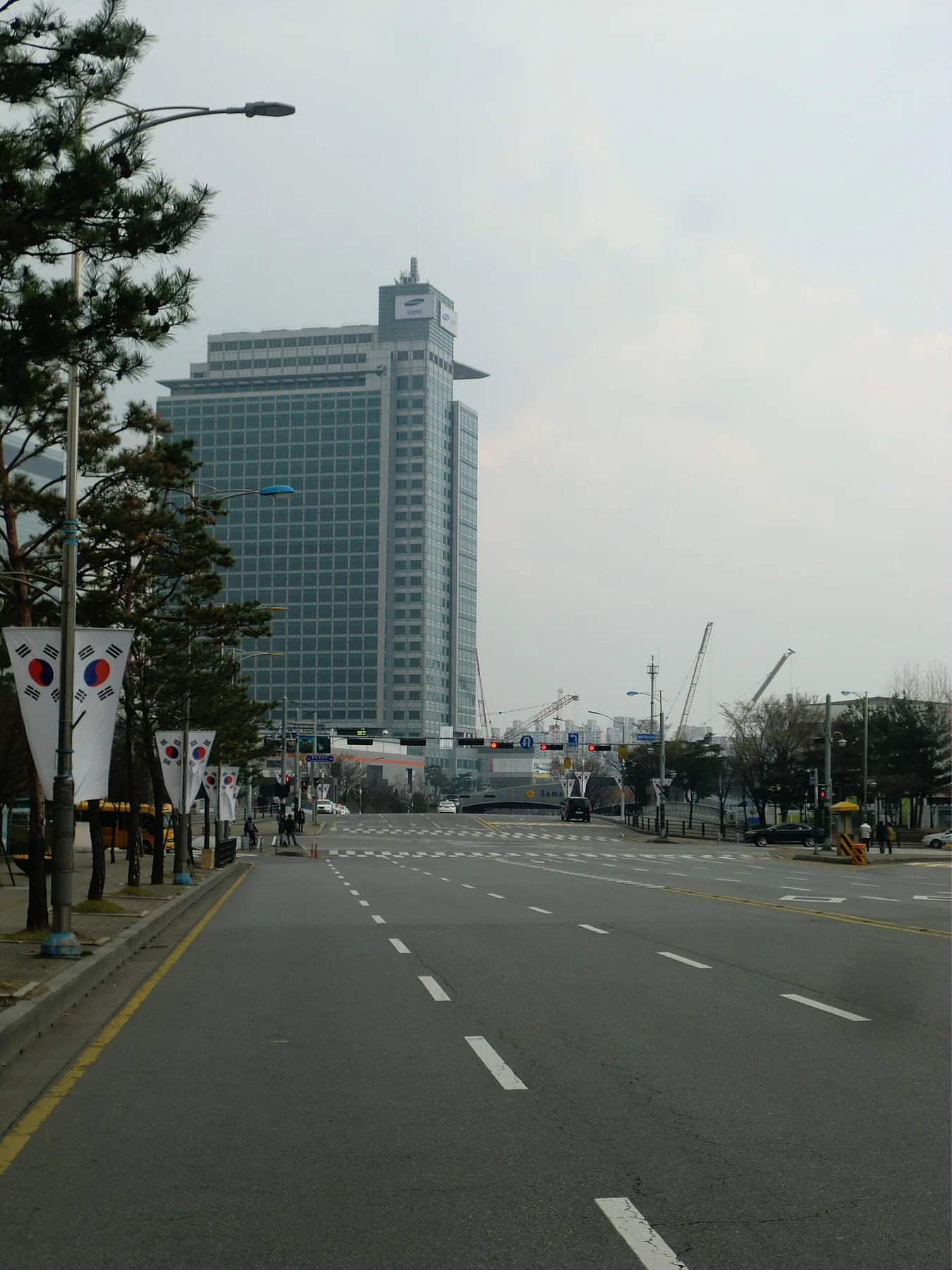 Samsung office tower beside a wide empty road lined with South Korean flags