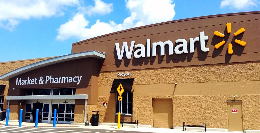 Walmart store front with the Walmart logo and a Market and Pharmacy entrance under a blue sky