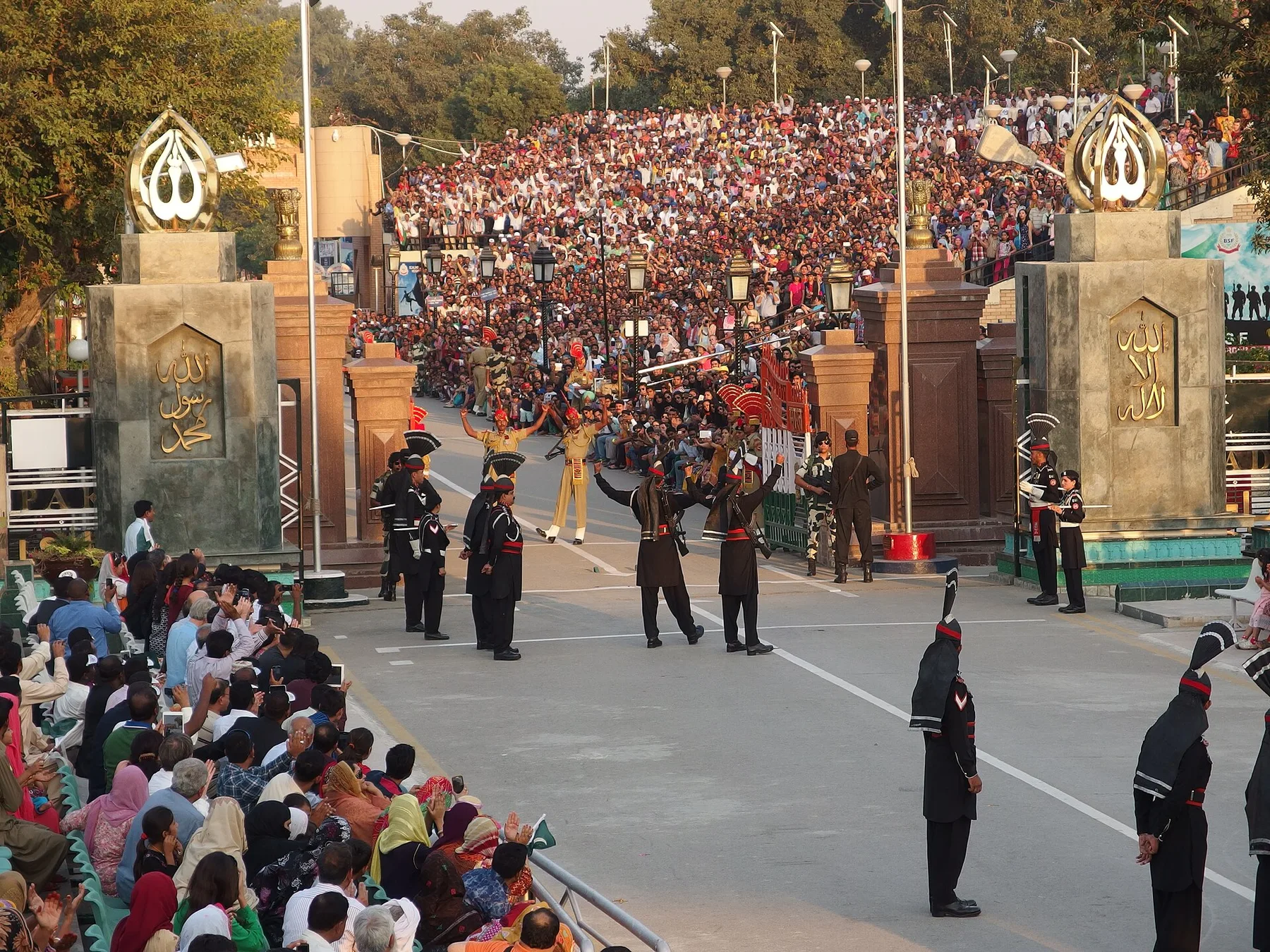 Pakistani Rangers in black uniforms march at the Wagah border gates as crowds cheer from packed stands