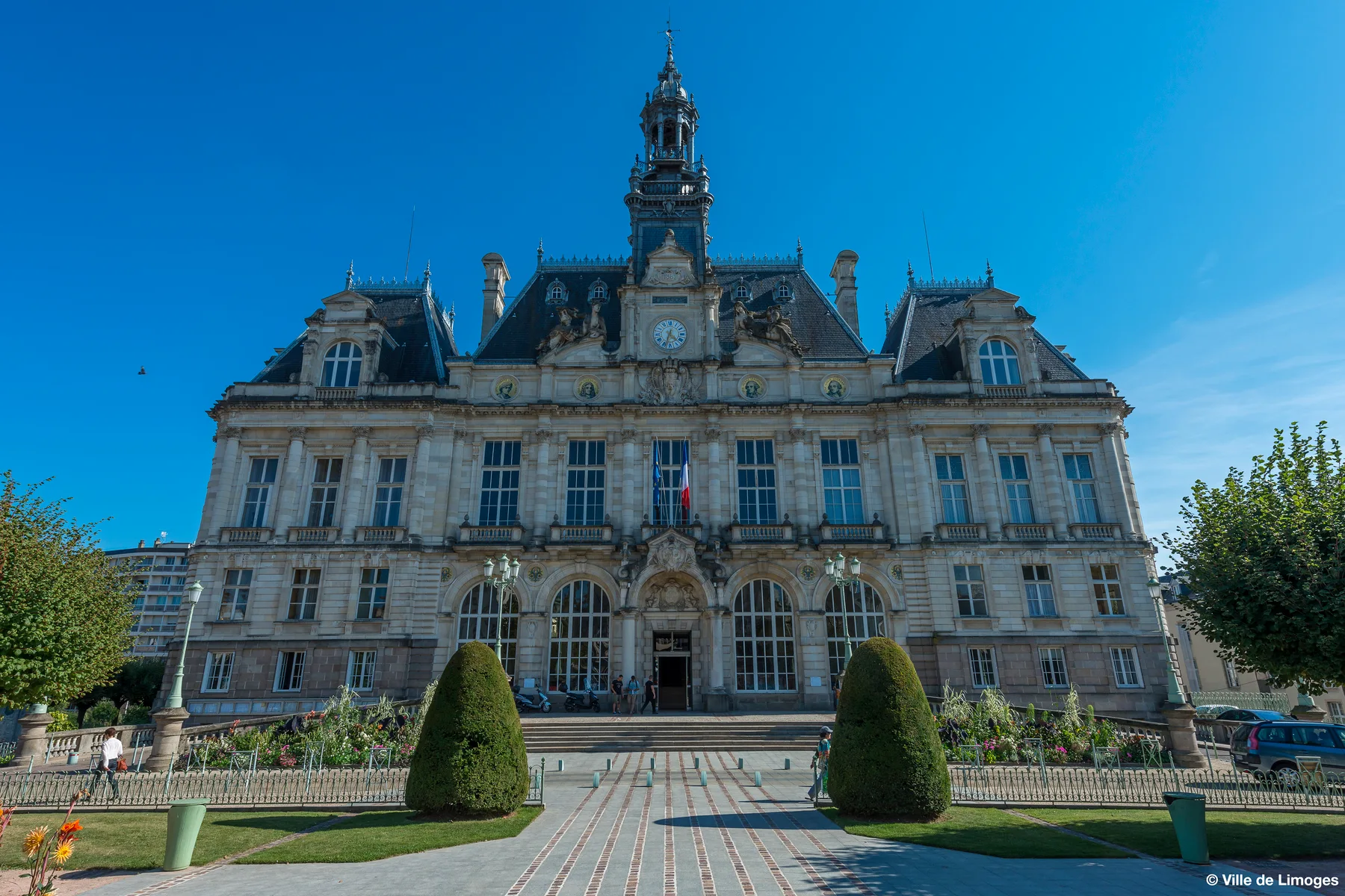 Limoges town hall with its central clock tower and French flags, seen on a sunny day before the fire