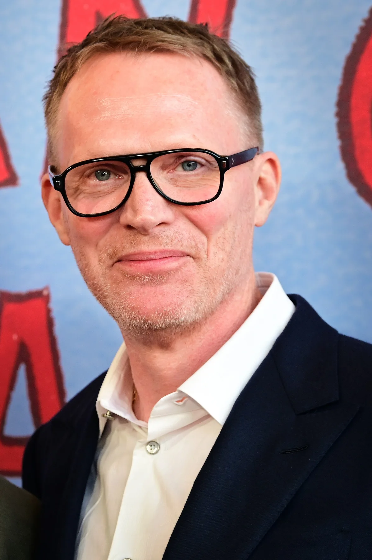 Paul Bettany in black-rimmed glasses, white shirt and navy jacket at a premiere