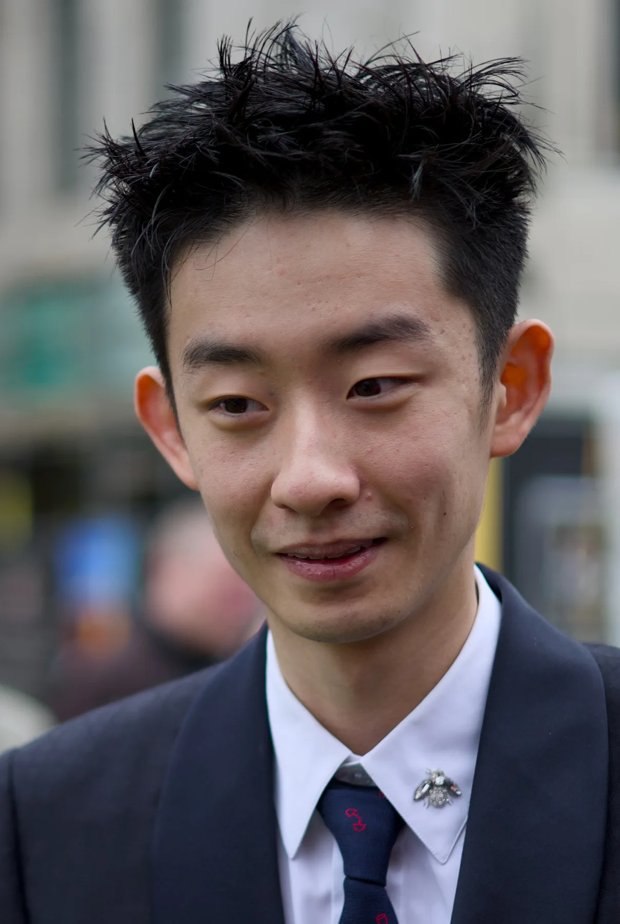 Wu Yize smiling in a navy suit and tie at the World Snooker green carpet ceremony