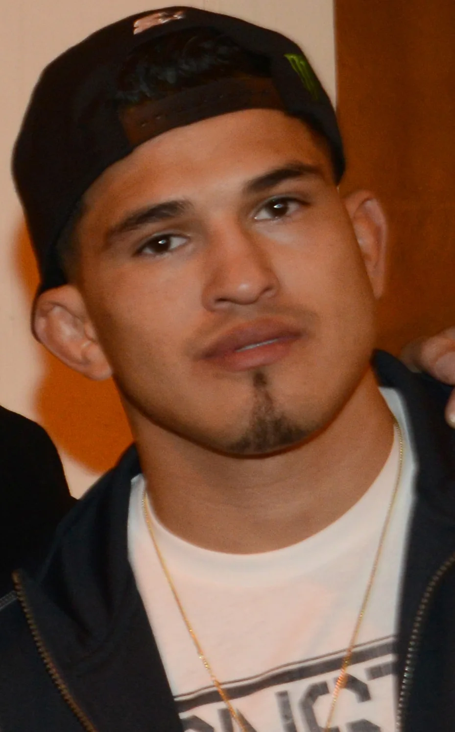 Anthony Pettis in a black cap, dark hoodie and white T-shirt, photographed close up