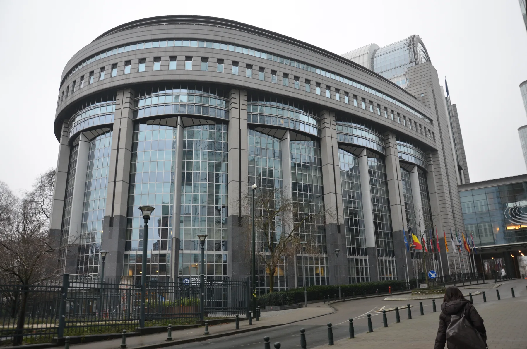 Curved glass facade of the European Parliament building in Brussels on a grey day