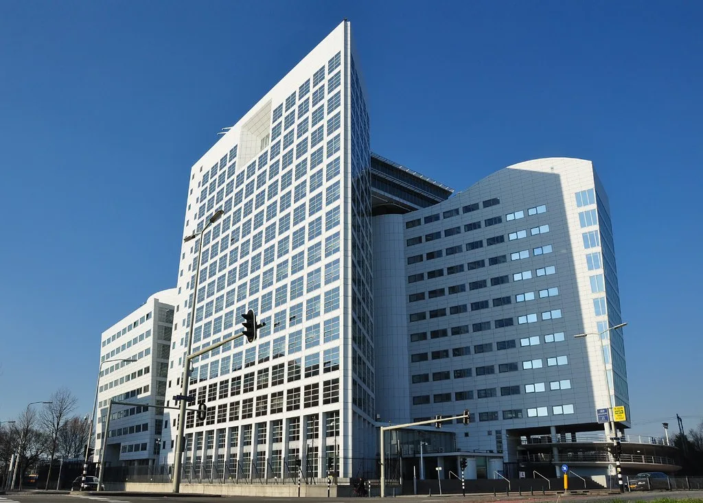White high-rise office building of the International Criminal Court in The Hague, with traffic lights in front