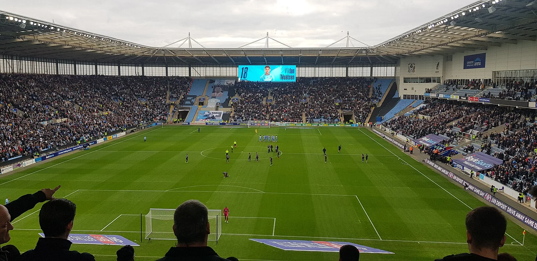 Players line up on the pitch at Coventry Building Society Arena in front of packed stands