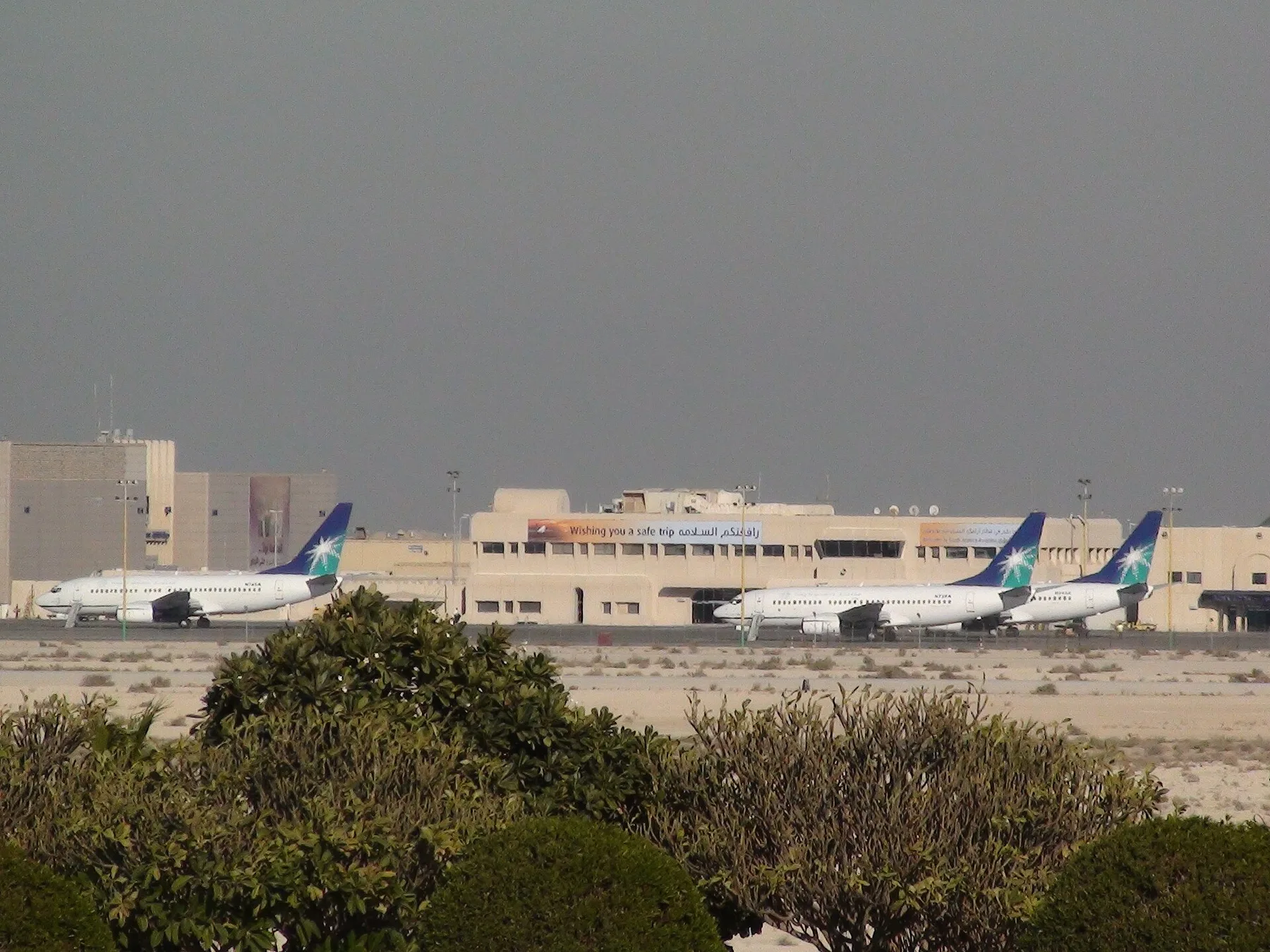 Saudi Aramco passenger jets parked in front of a terminal building at King Fahd International Airport, Dammam