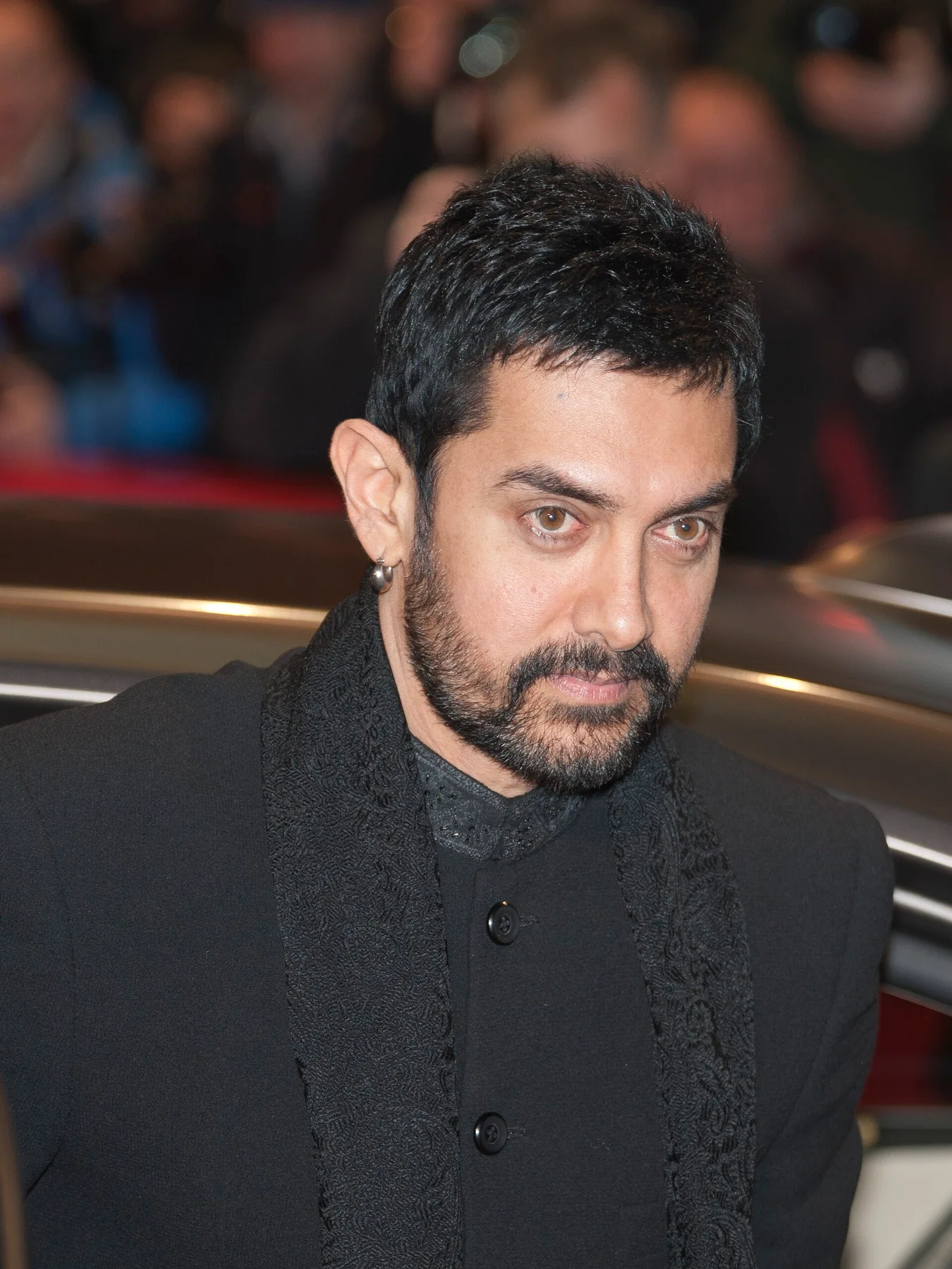 Aamir Khan in a black sherwani and scarf stepping out of a car at a red carpet event
