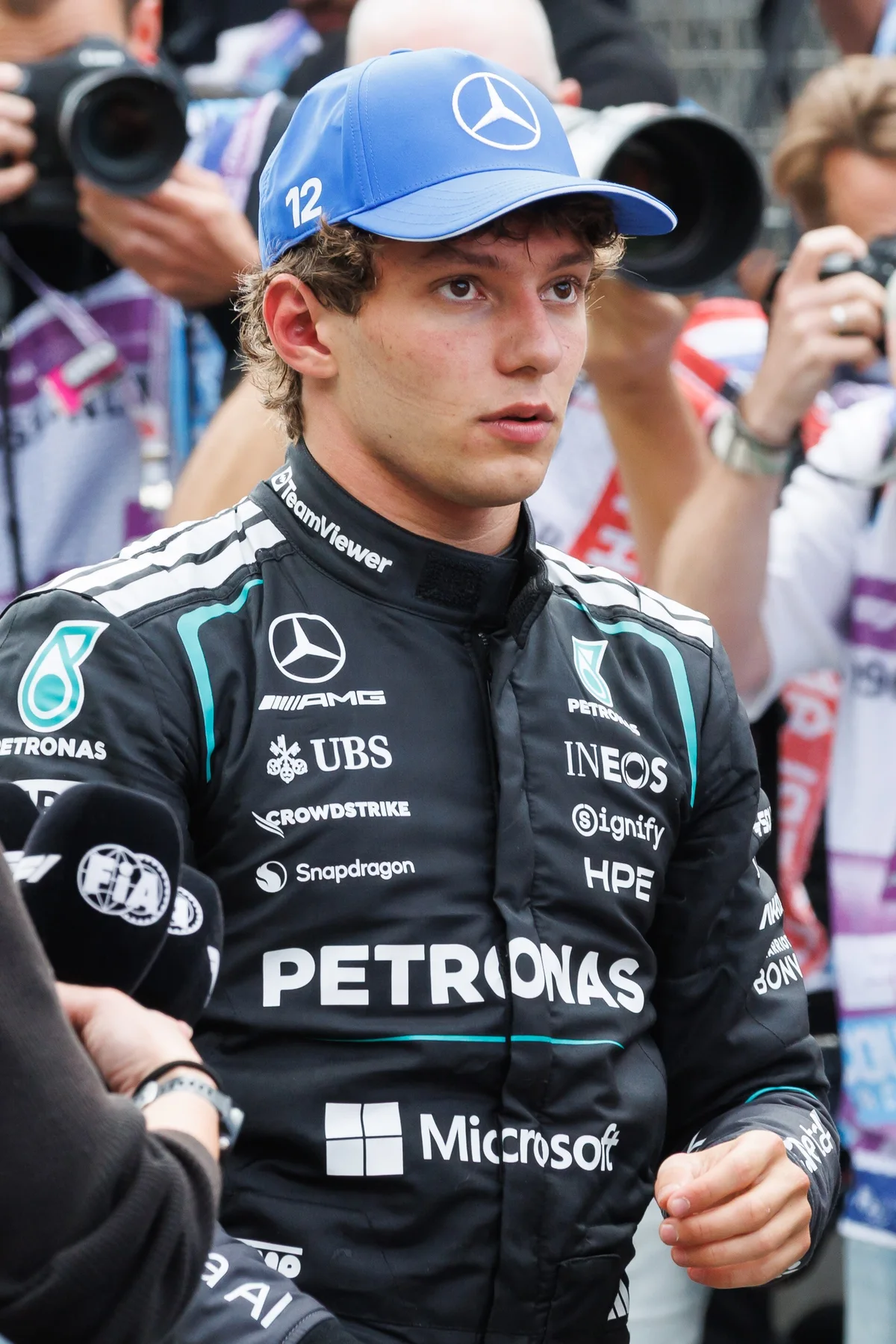 Kimi Antonelli in Mercedes race suit and blue number 12 cap, surrounded by photographers