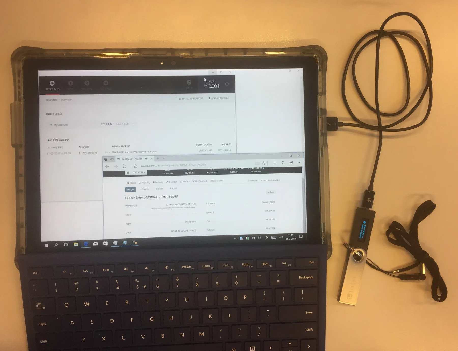 Ledger Nano hardware wallet plugged by USB cable into a tablet showing a Bitcoin wallet account screen