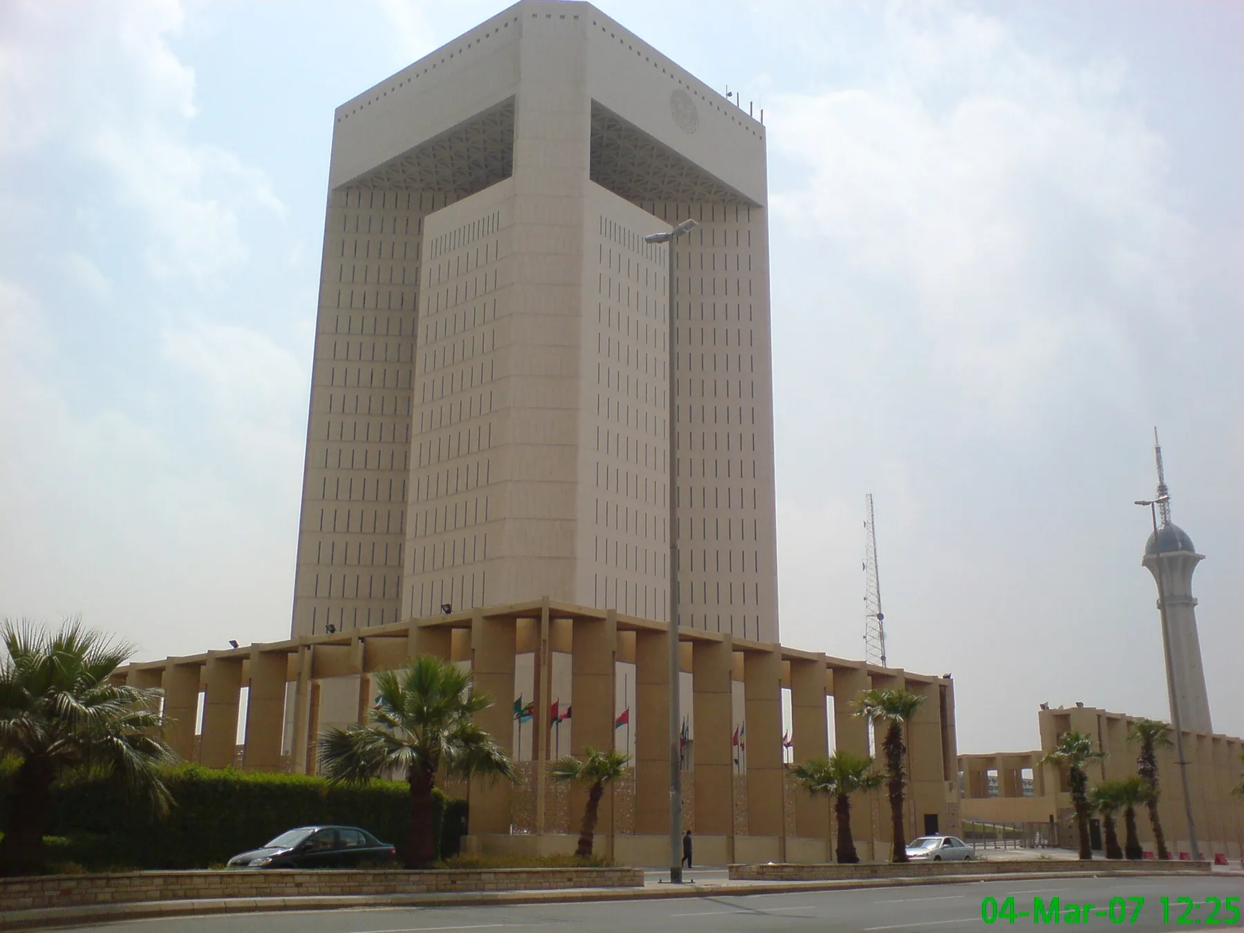 Islamic Development Bank headquarters tower in Jeddah with palm trees and a colonnade at its base