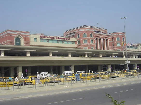 Allama Iqbal International Airport terminal in Lahore with yellow taxis lined up at the kerb