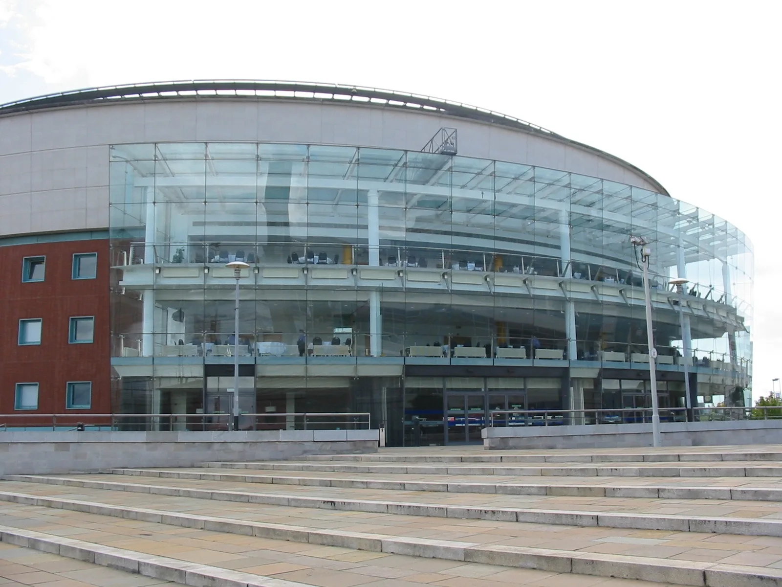 Glass-fronted curved facade of the Waterfront Hall in Belfast with wide stone steps in front
