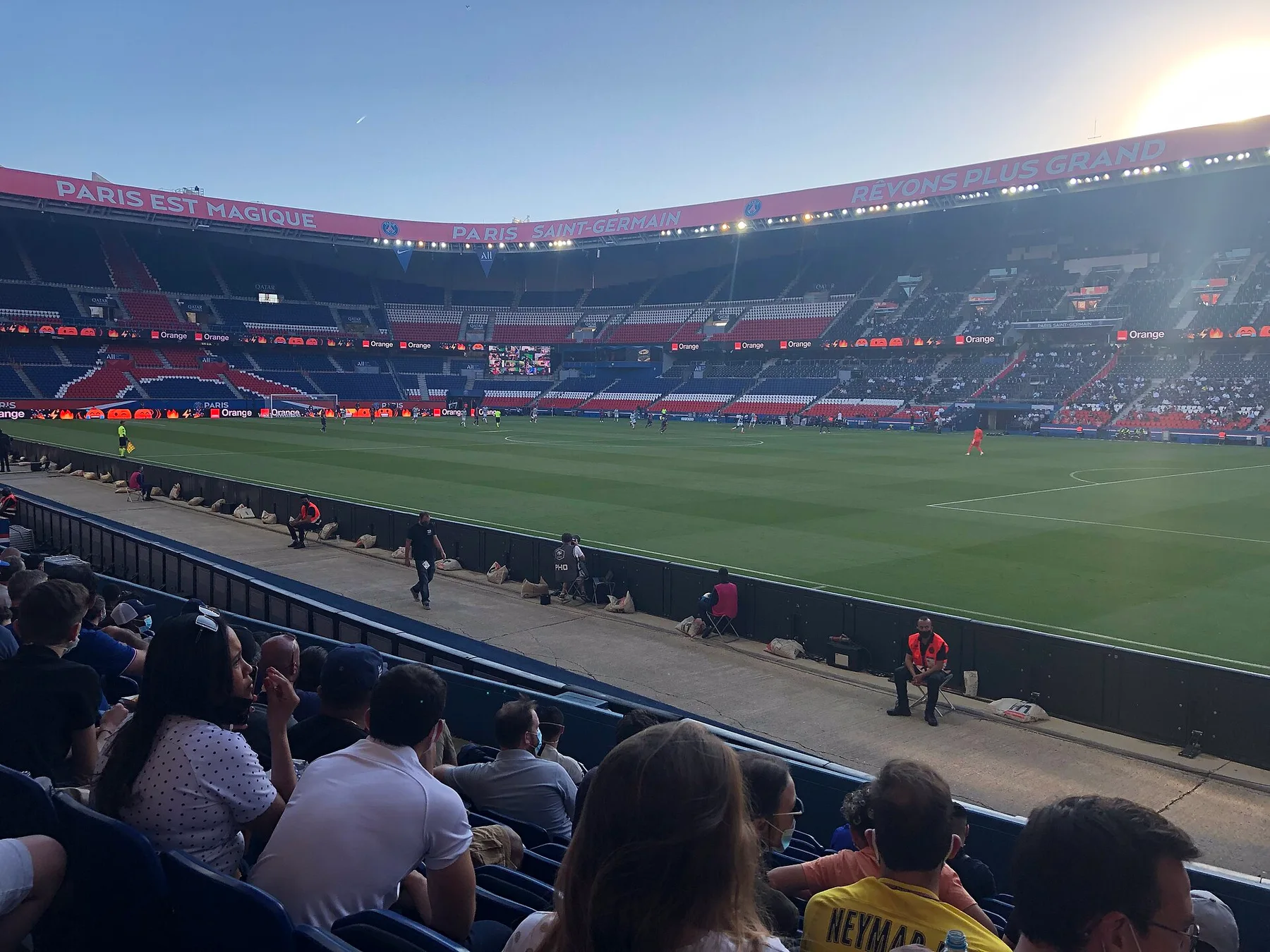 Fans in the stands at the Parc des Princes in Paris, looking across the pitch at sunset