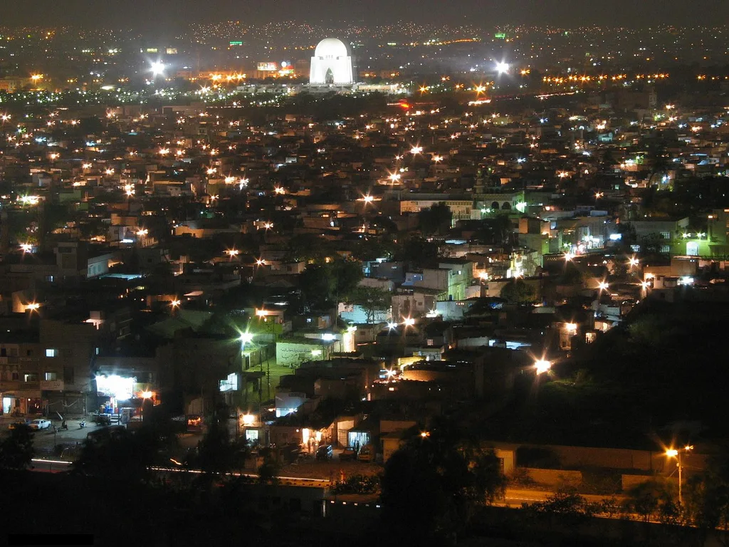 Mazar-e-Quaid lit up at night above the dense lights of Karachi neighbourhoods