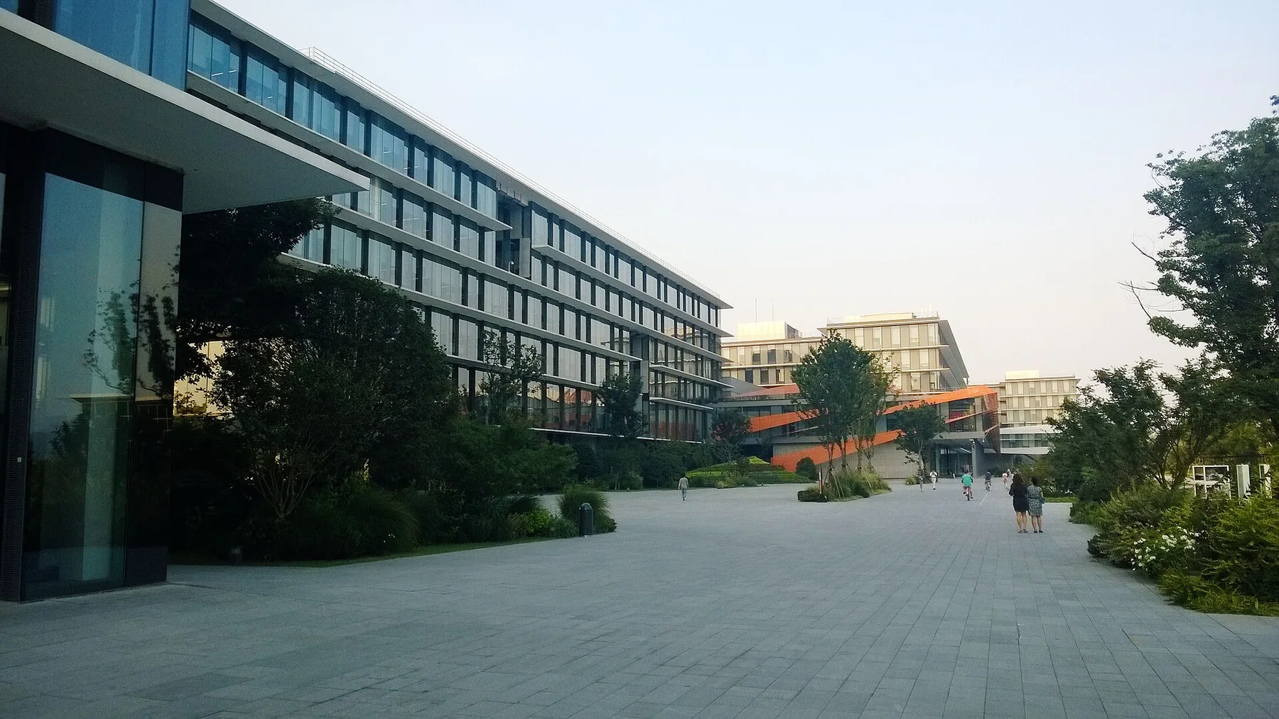 Modern glass office blocks and a wide paved walkway on an Alibaba office campus