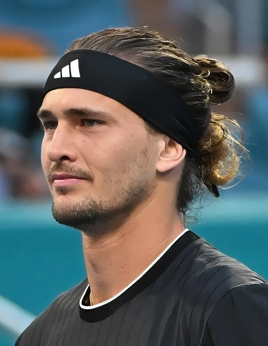 Alexander Zverev in a black headband and black shirt on a tennis court, looking to his right
