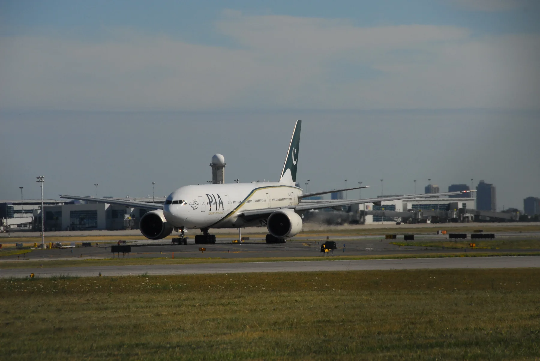 A PIA Boeing 777 with the green tail and crescent taxiing on an airport runway