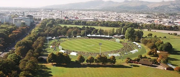 Aerial view of Hagley Oval cricket ground in Christchurch, ringed by trees with the city behind
