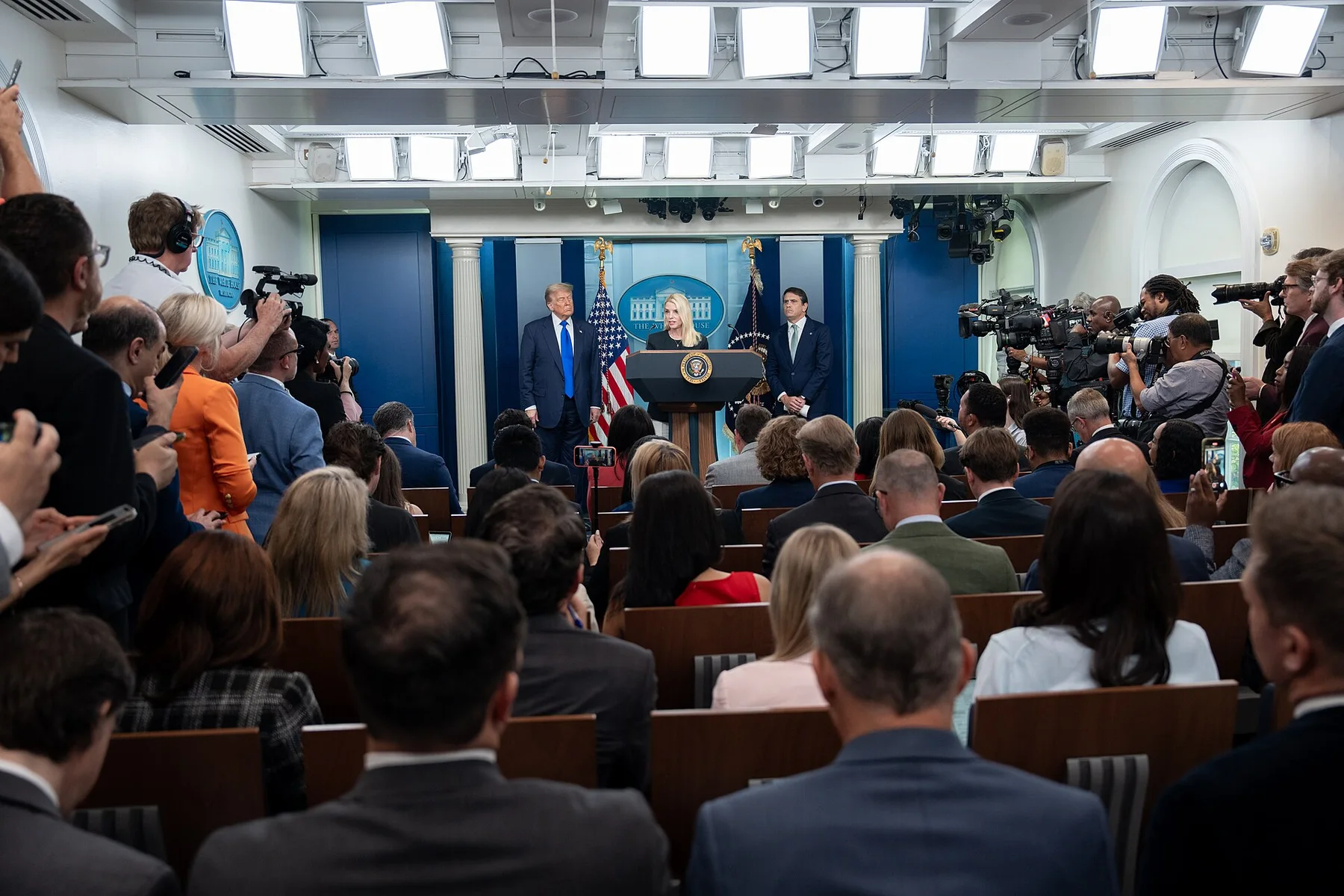 Reporters and TV cameras fill the White House briefing room as Donald Trump stands at the podium