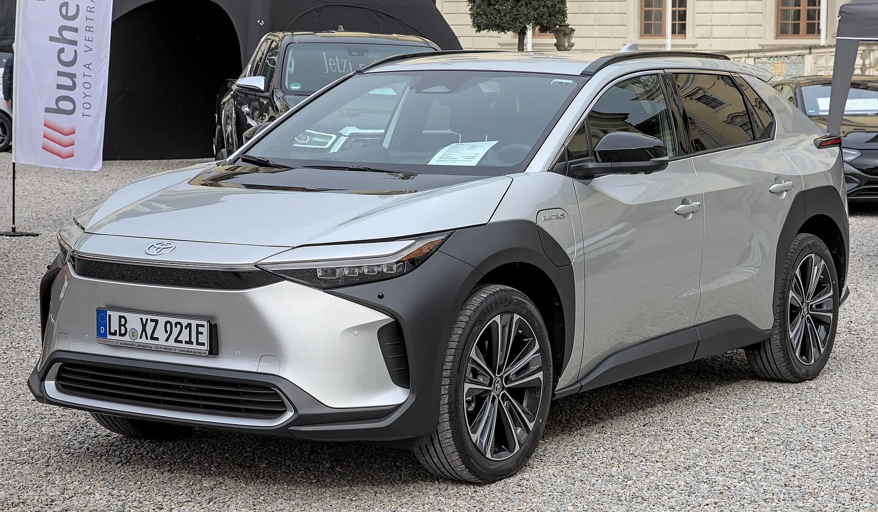 Silver Toyota bZ4X electric SUV parked on gravel outside a dealer display tent