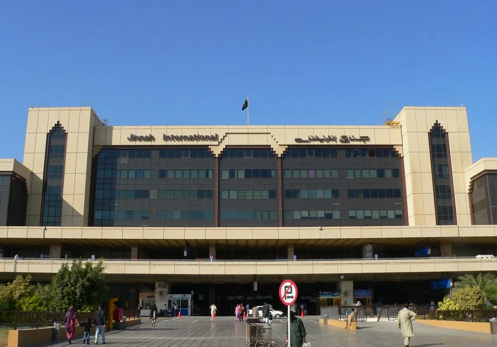 Front of the Jinnah International terminal building in Karachi with travellers and trolleys on the forecourt