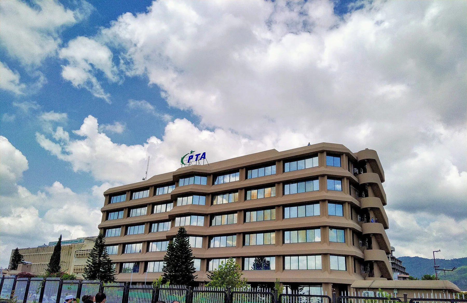 PTA headquarters building in Islamabad with the PTA logo on its roof under a cloudy blue sky