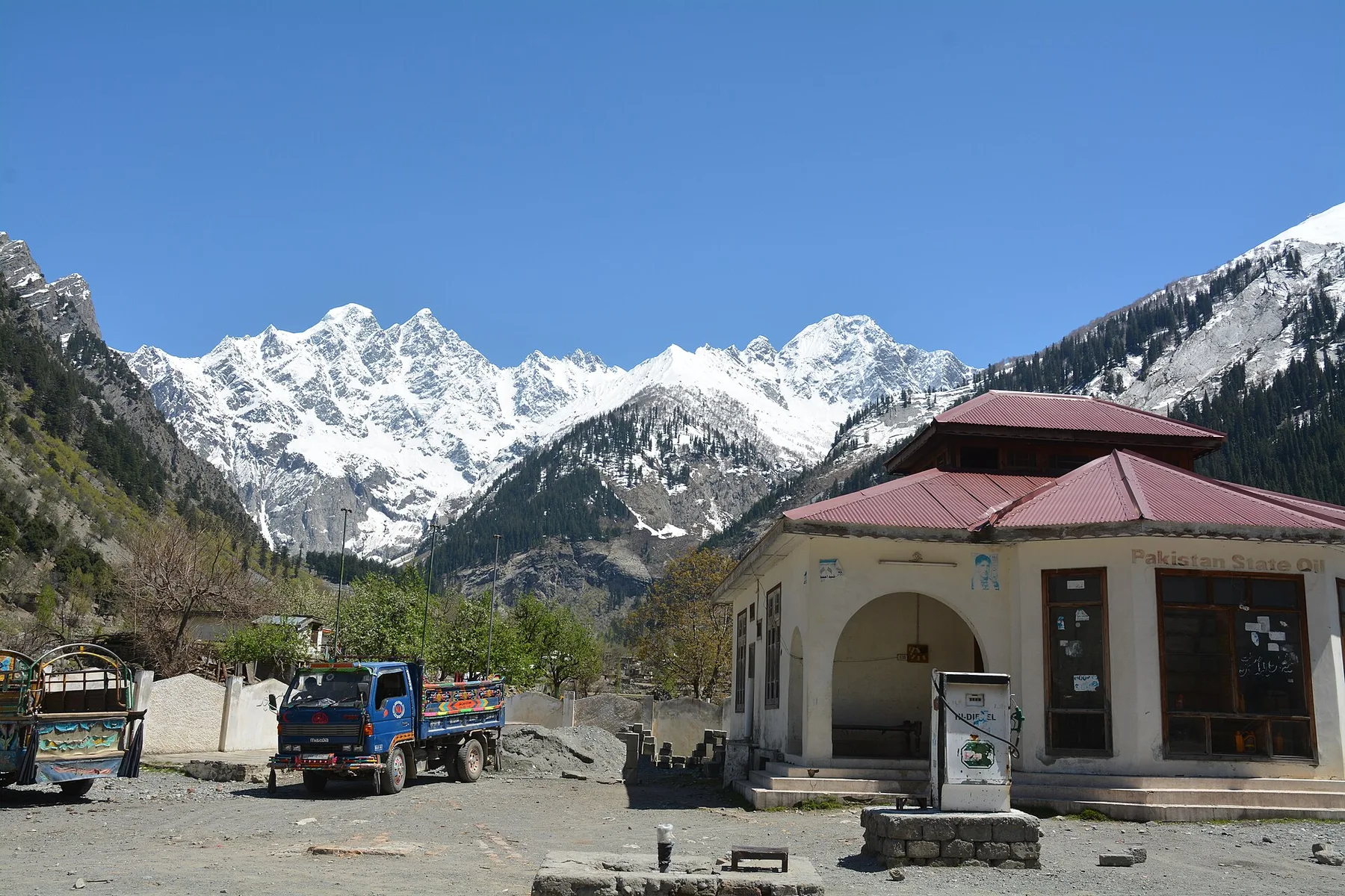 Pakistan State Oil fuel station with a diesel pump and a blue truck below snow-covered mountains