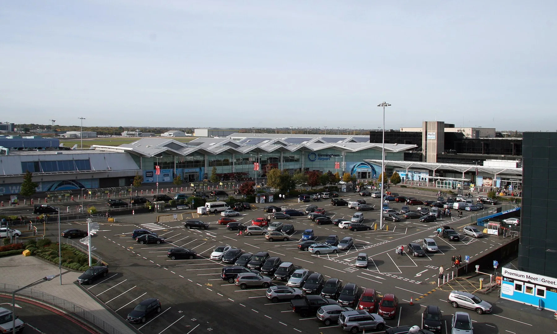 Birmingham Airport terminal building seen across a busy short-stay car park on a clear day