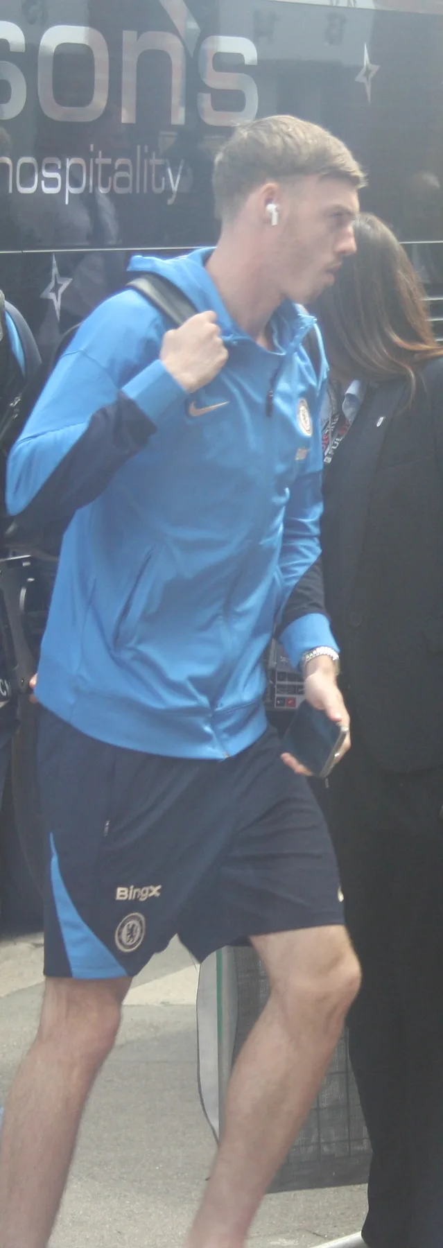 Cole Palmer in a blue Chelsea training jacket and shorts arriving at the stadium with a backpack