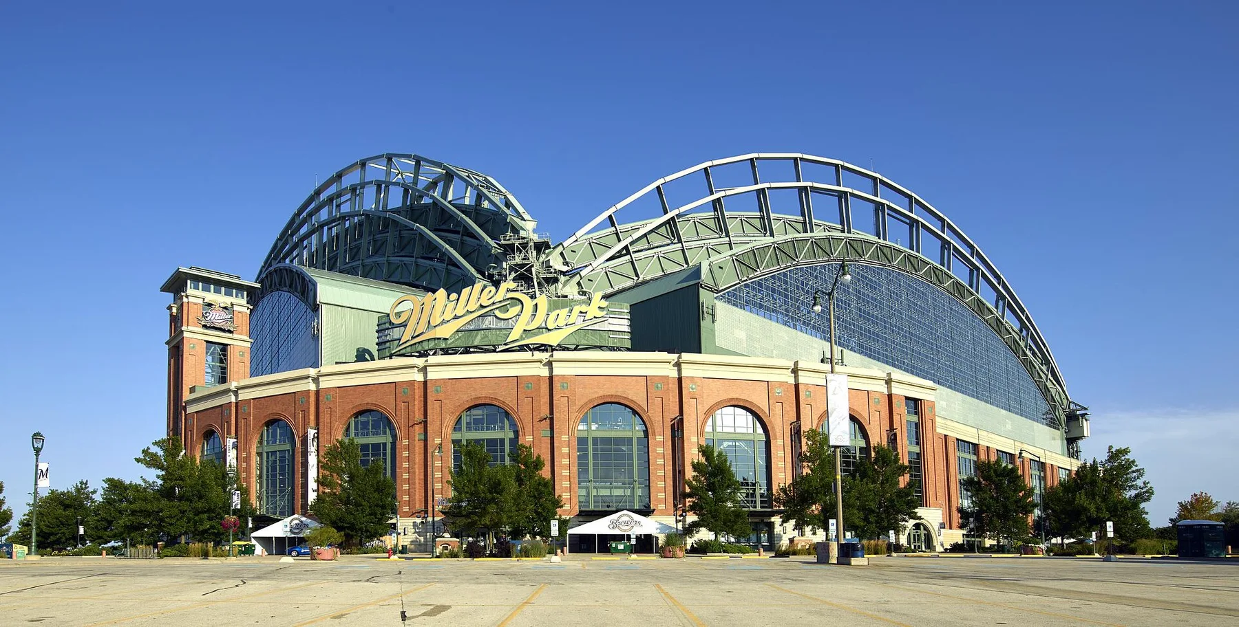 Brick facade and arched steel roof of the Brewers ballpark in Milwaukee under a clear blue sky