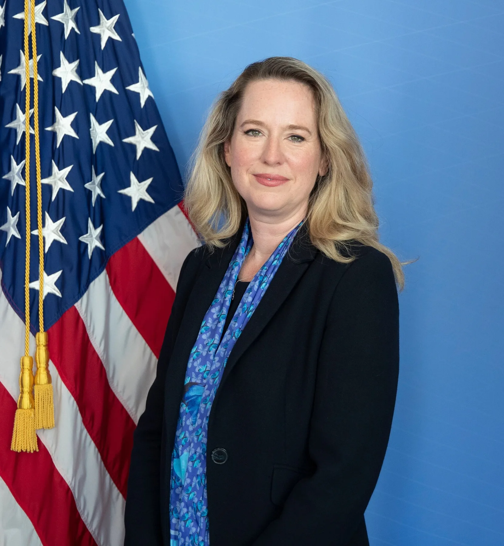 Amy Pope, IOM director general, in an official portrait in a dark jacket and blue scarf