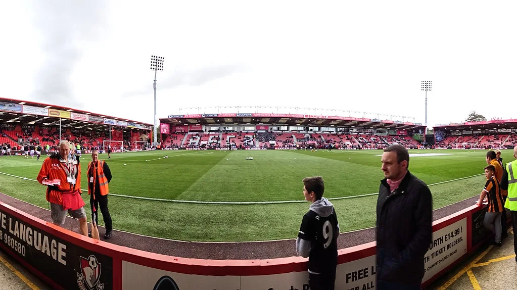 Bournemouth's stadium before kick-off, AFCB spelled out in red seats, stewards and fans by the pitch