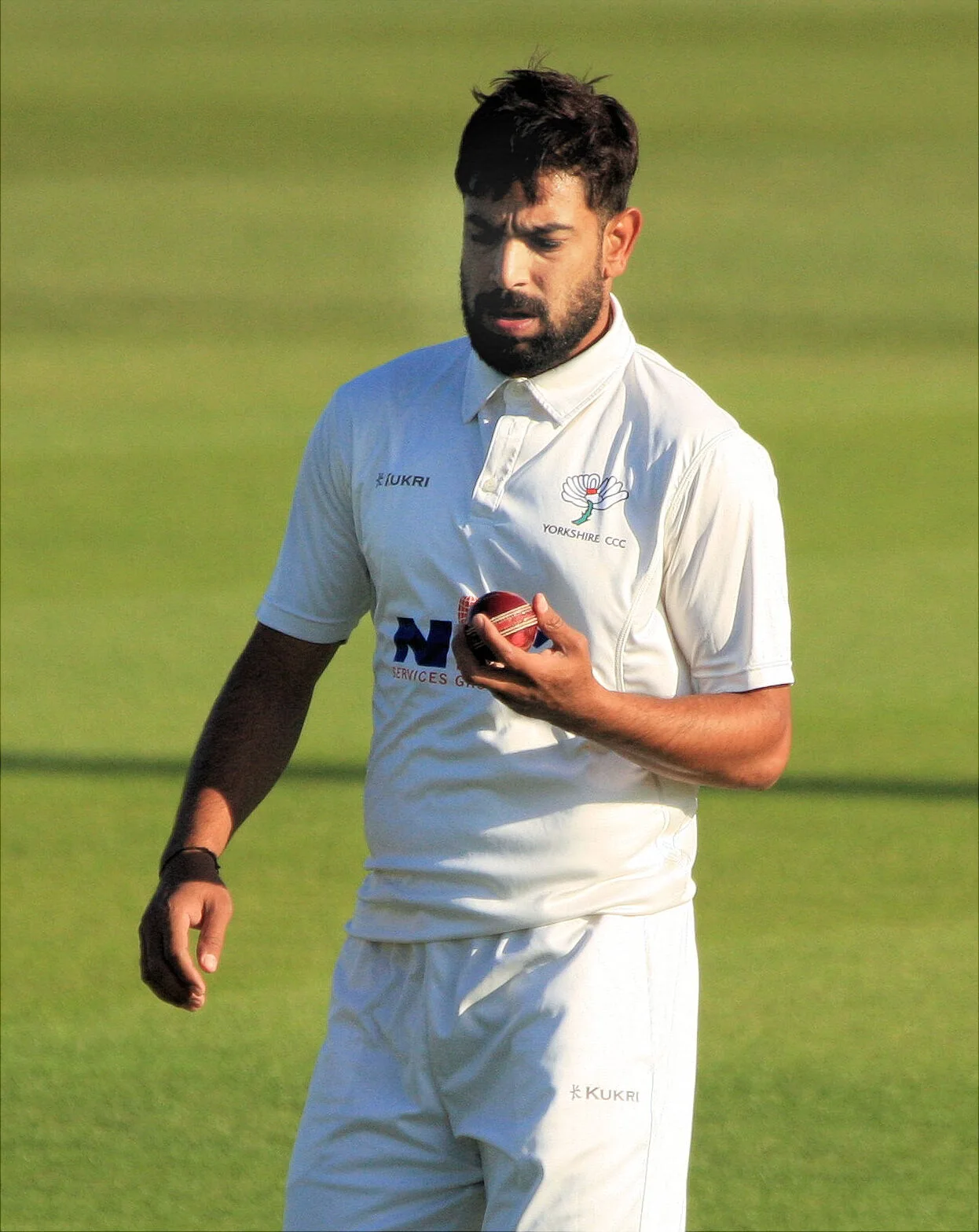 Haris Rauf in Yorkshire whites holding a red cricket ball on the outfield