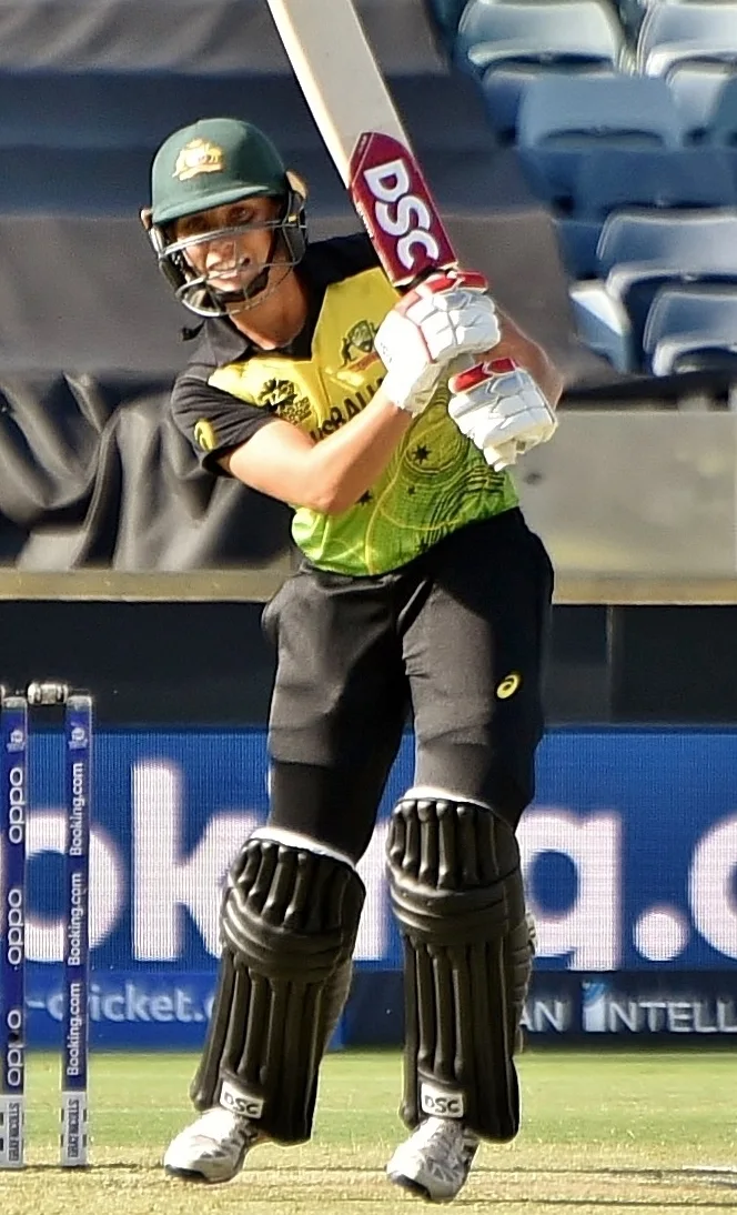 Ashleigh Gardner batting for Australia in green and gold kit, following through on a drive