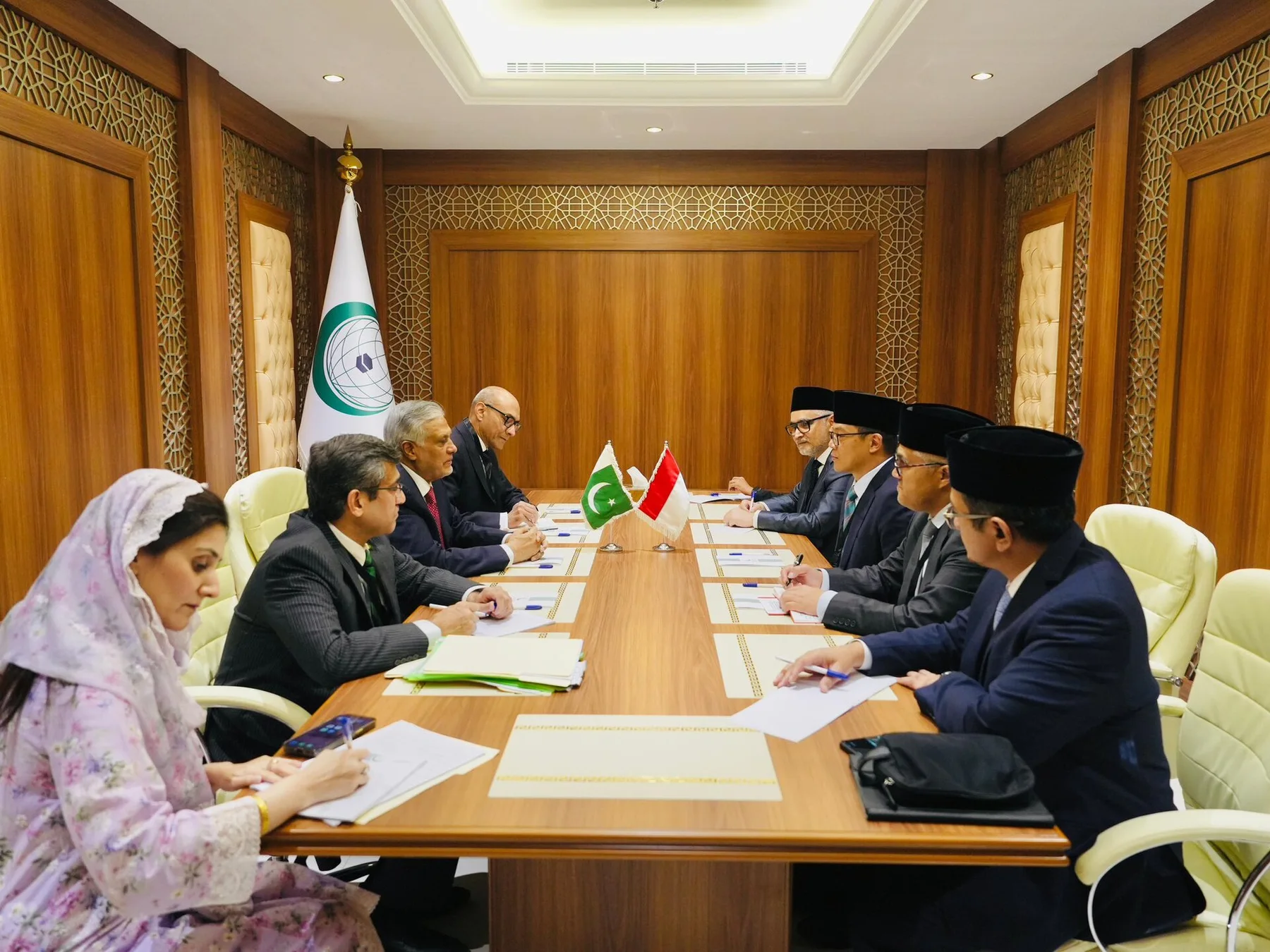 Ishaq Dar and Pakistani officials at a wood-panelled meeting table facing a delegation, Pakistani flag between them