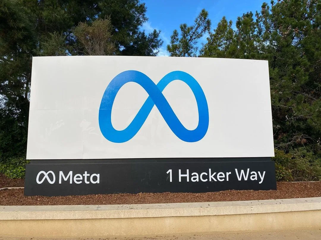 Meta infinity logo sign at 1 Hacker Way, the company headquarters, under a blue sky