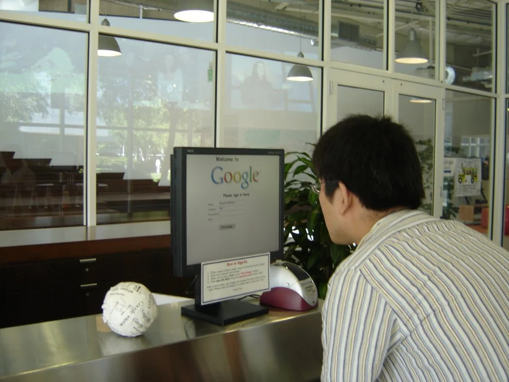 Visitor at a Google office reception desk signing in on a screen showing the Google logo