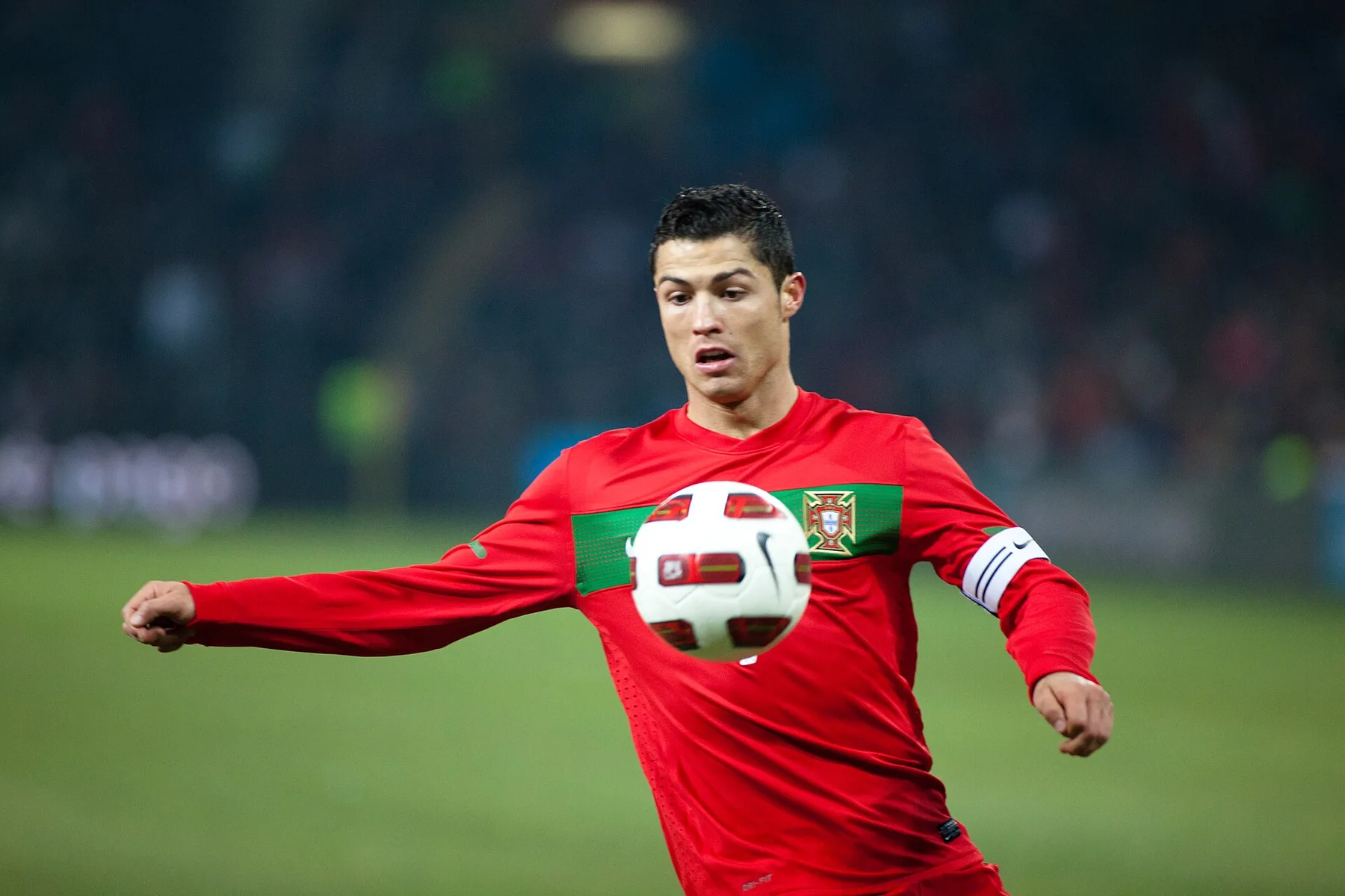 Cristiano Ronaldo in a red Portugal shirt and captain armband controlling the ball during a match