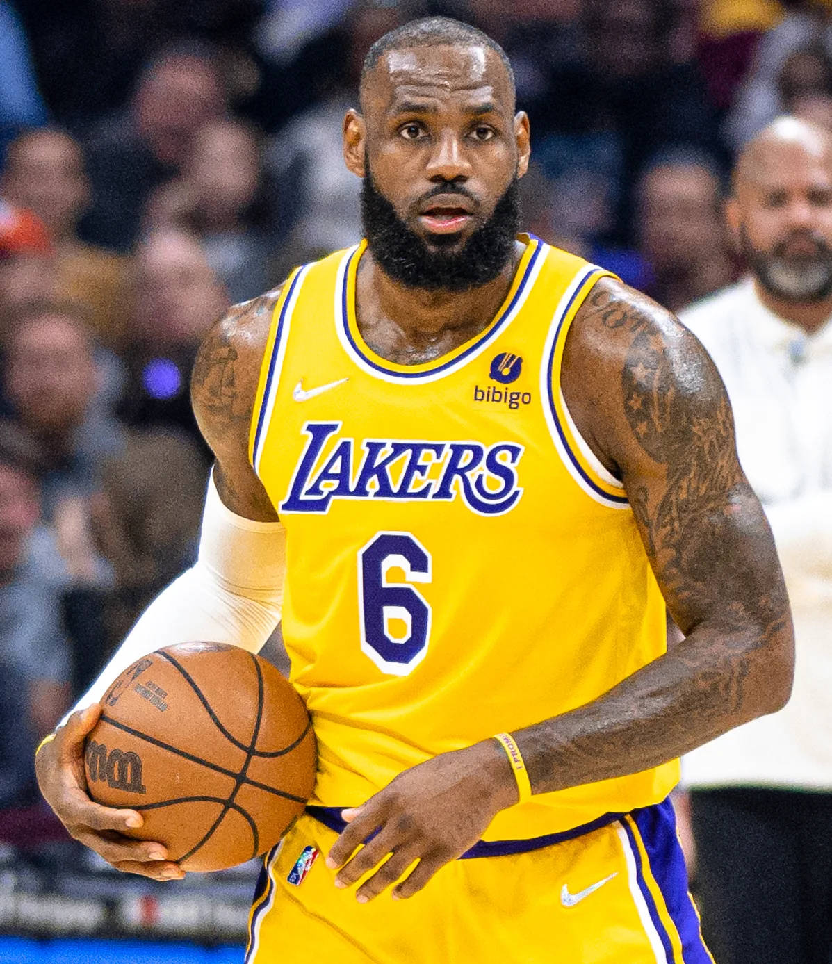 LeBron James in a yellow Lakers number 6 jersey holding a basketball during an earlier NBA game