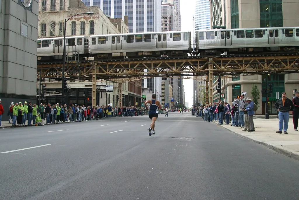 A marathon runner passes under the elevated L train in downtown Chicago as spectators line both sides of the street