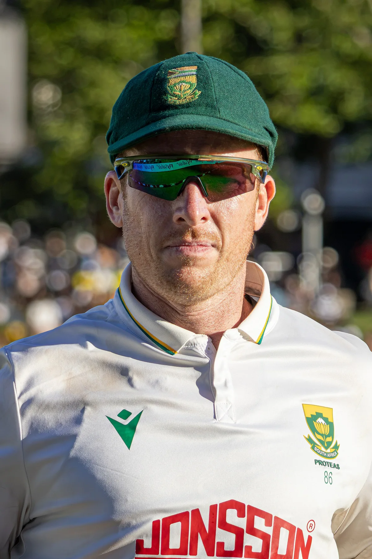 Simon Harmer in a South Africa Test cap and sunglasses walking out at a cricket ground
