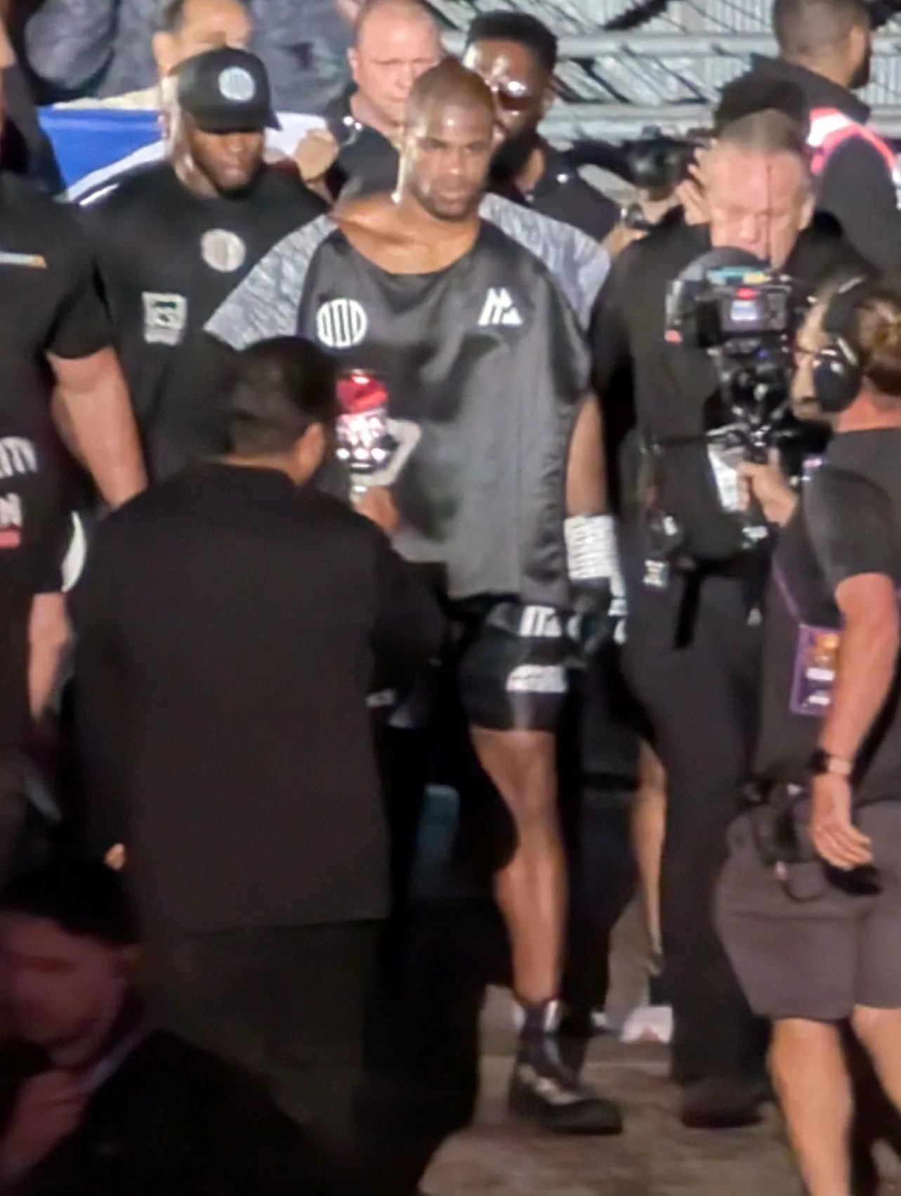 Daniel Dubois in gloves and shorts walking to the ring surrounded by his team and a TV camera