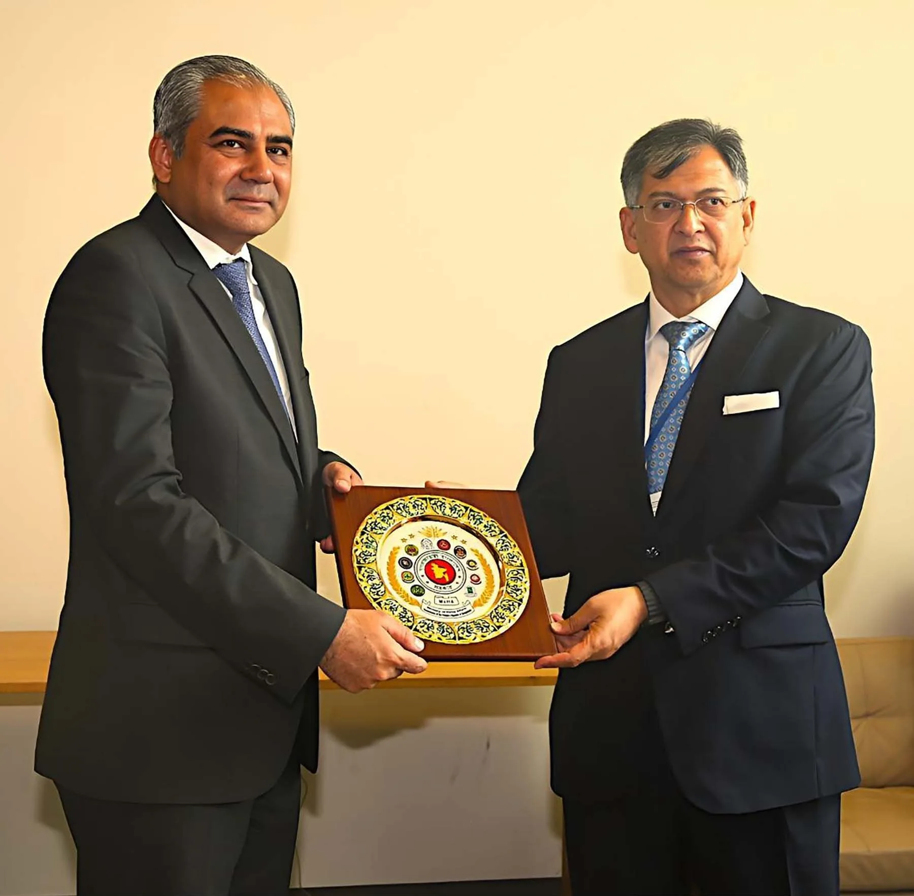 Interior Minister Mohsin Naqvi in a dark suit holding a souvenir plaque with a visiting official