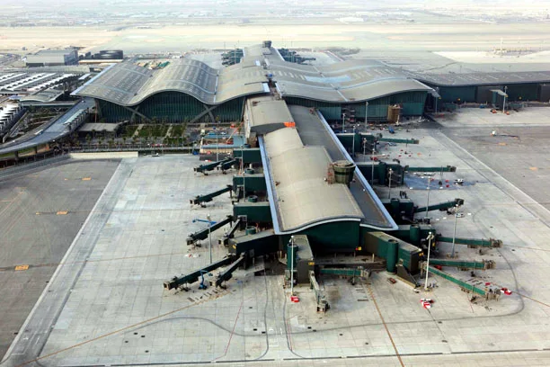Aerial view of Hamad International Airport terminal in Doha with curved roofs and jet bridges