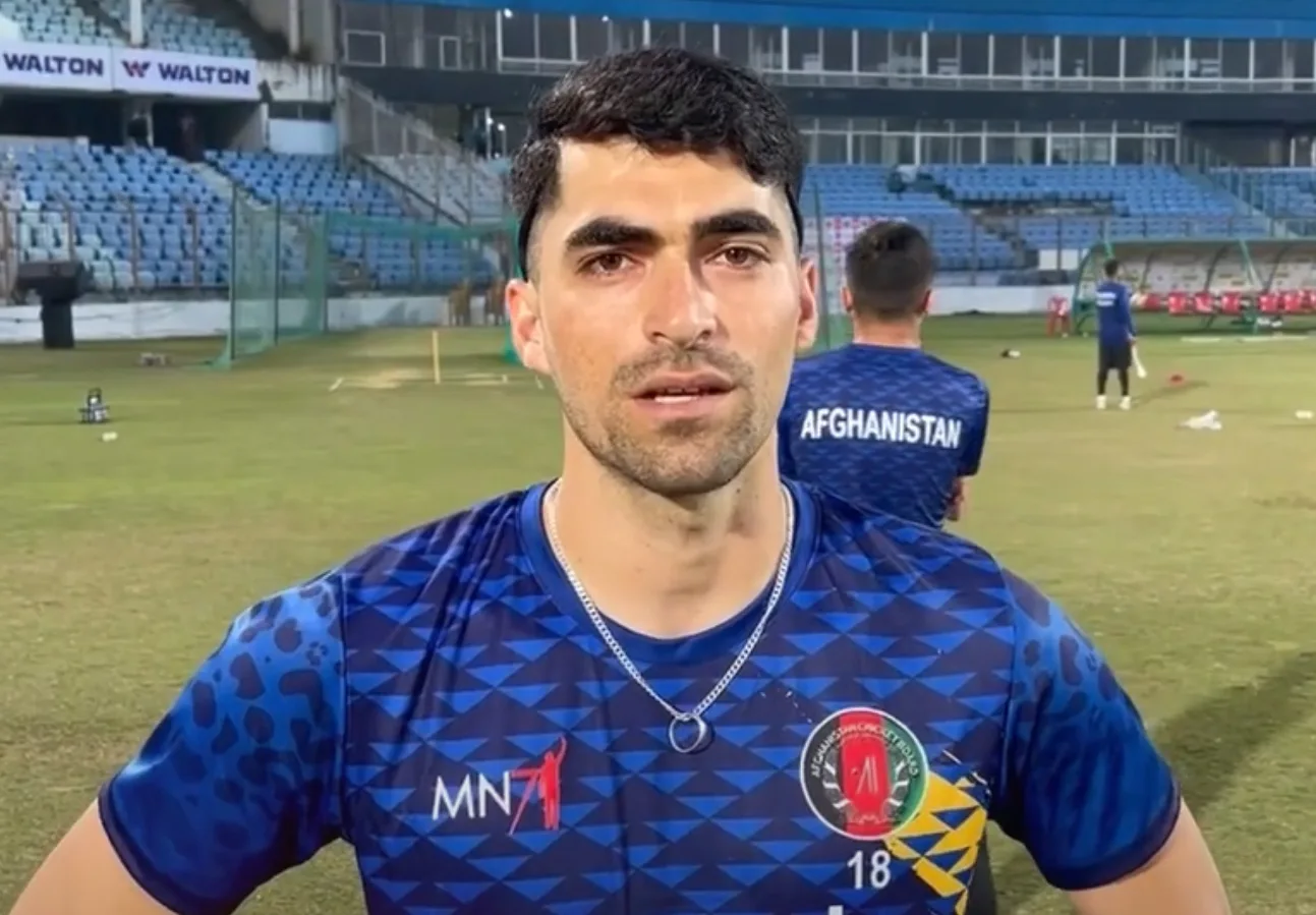 Afghanistan cricketer in the blue national team training shirt speaking on the field during a practice session