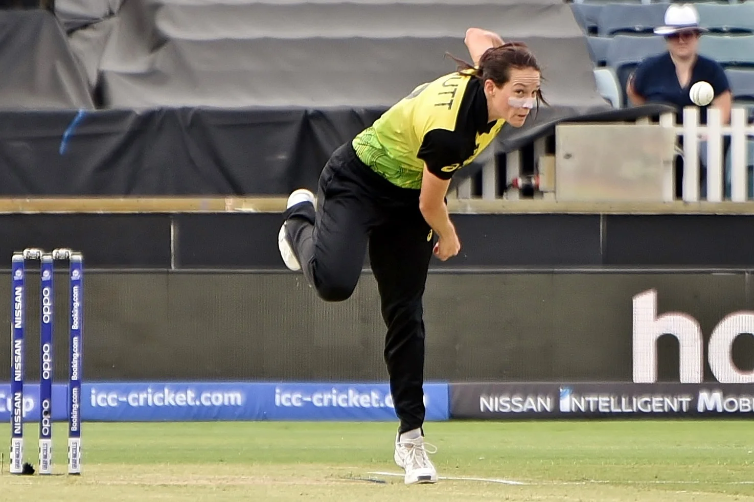 Megan Schutt in Australia yellow and black kit follows through after bowling at a T20 World Cup match
