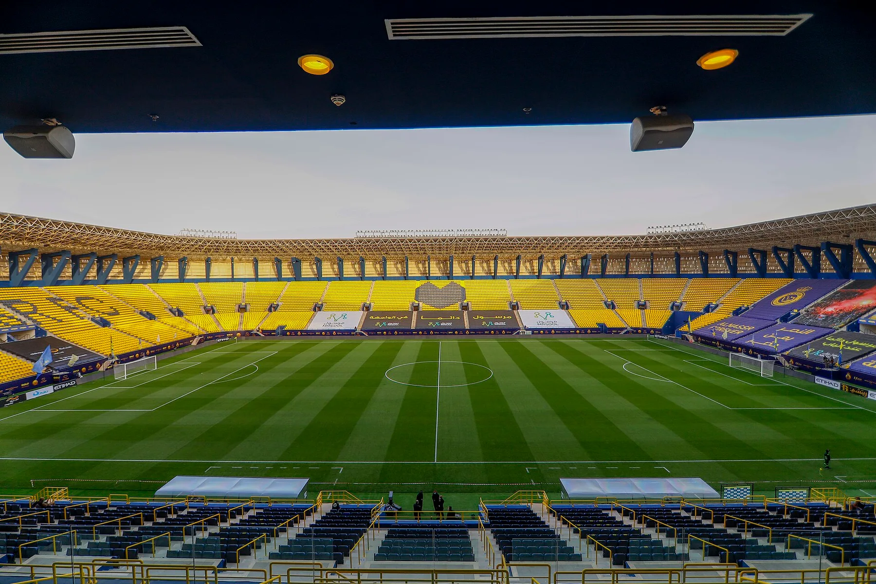 Empty yellow stands and pitch at Al Nassr's home stadium in Riyadh, seen from the covered upper tier