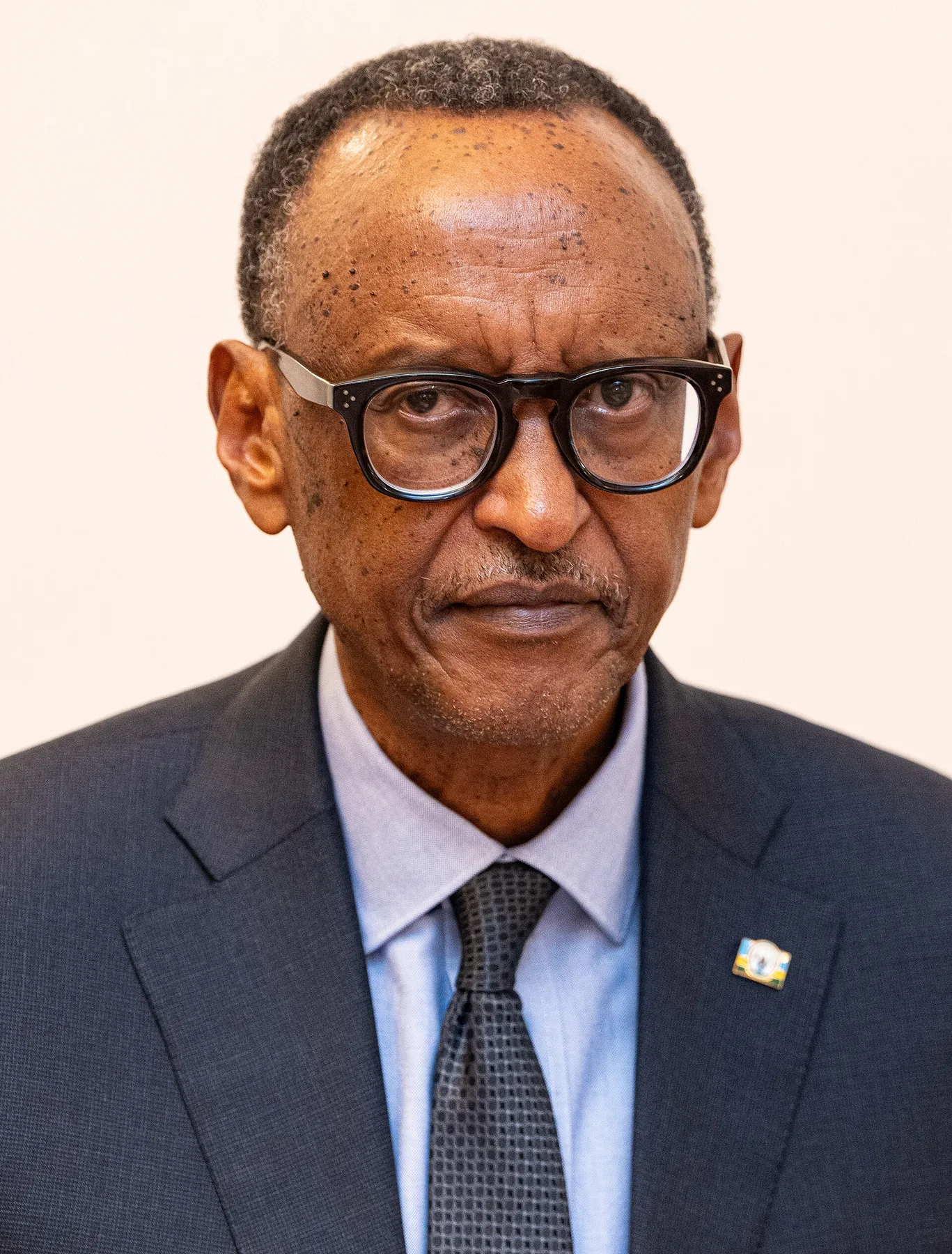Rwandan President Paul Kagame in glasses, a dark suit and tie with a Rwanda flag pin